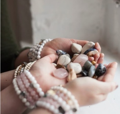 Manos con pulseras de piedras naturales sosteniendo piedras pulidas